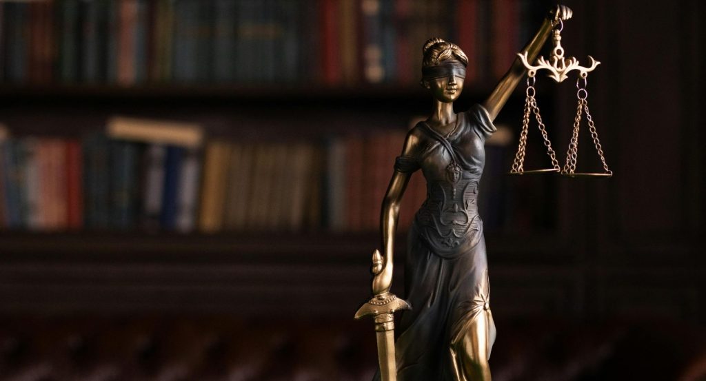 Lady Justice and gavel on a table in a classic law library setting.